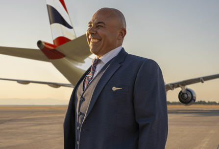 Member of British Airways cabin crew standing in front of plane